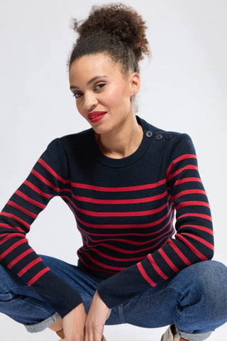 Woman wearing navy blue and red striped sweater with button detail, casual jeans