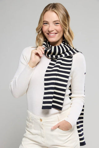 Woman wearing a navy and white striped scarf with a cream sweater and pants
