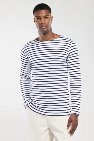 Man wearing white navy striped long sleeve shirt and light pants on white background