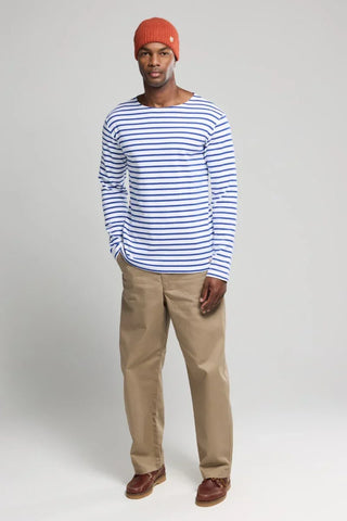 Man wearing blue and white striped long sleeve shirt, beige pants, red knit beanie, and brown shoes