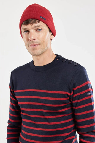 Man wearing red beanie and navy sweater with red stripes and shoulder buttons