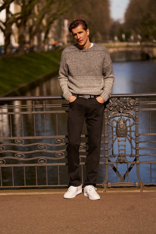 Man in a grey knit sweater and black Meyer pants by a river, fall winter fashion