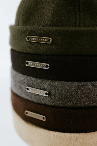 Stack of wool beanies in assorted colors with metal Crowncap labels, close-up view