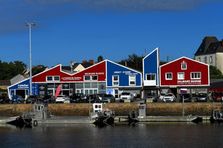 Waterfront view of colorful marine clothing stores and small boats docked by the harbor