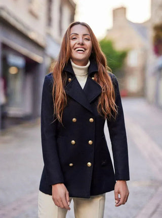 Woman wearing navy double-breasted pea coat with gold buttons and turtleneck sweater
