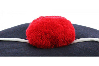 Close-up of navy marine hat with red pompom and white cord accessory