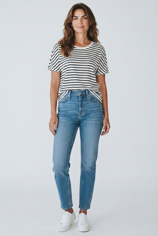 Modèle portant le t-shirt rayé en lin noir et blanc BRAX Caelen avec un jean bleu et des baskets blanches
