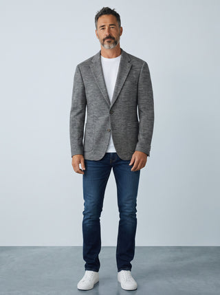 Homme portant un veston Digel en jersey de laine gris coupe Modern Fit avec un t-shirt blanc et un jean bleu