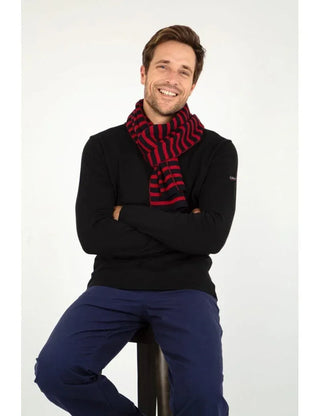 Man wearing a red and navy striped wool scarf over a black sweater and blue pants