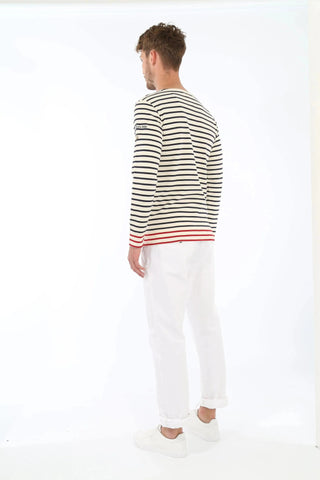 Man wearing striped long-sleeve shirt with red trim and white pants, back view