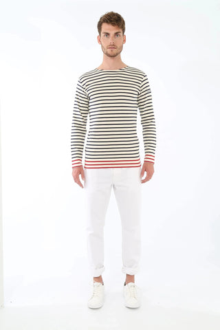 Man wearing a striped long-sleeve shirt with red accents, white pants, and white sneakers