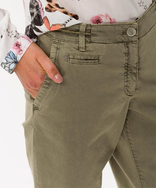 Close-up of woman's hand in pocket of olive green cotton pants with floral blouse