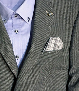 Grey wool blazer with textured fabric, blue dress shirt, and patterned pocket square