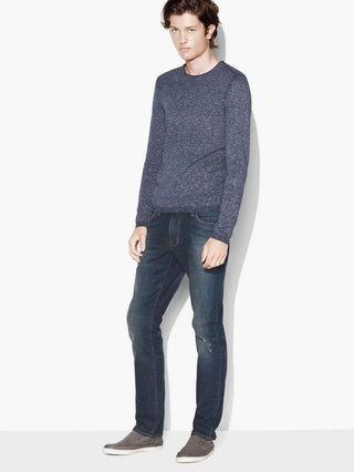 Man wearing a blue crew neck cotton sweater with dark jeans and grey slip-on shoes