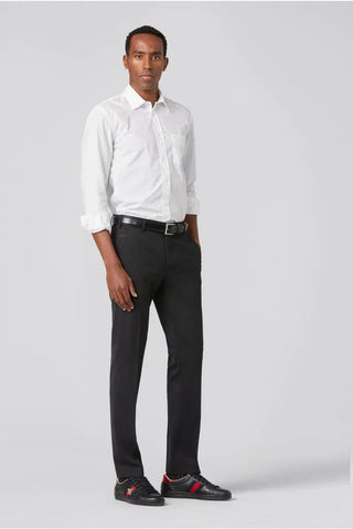 Man wearing slim-fit black wool pants, white dress shirt, black belt, and black sneakers