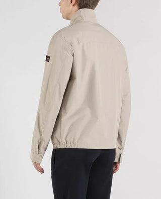 Back view of man wearing beige nylon jacket with patch on sleeve, casual outerwear